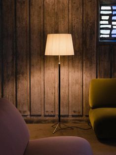 a living room with a couch, chair and lamp in front of a wooden wall