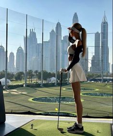 a woman standing on top of a green field holding a golf club