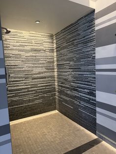 an empty bathroom with black and white tiles on the walls, shower stall door open