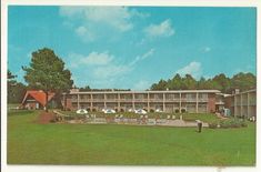 an old photo of a motel in the middle of a field with people walking around