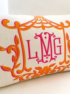 an orange and pink decorative pillow with the letter lmg on it's side