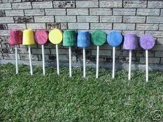 colorful lollipops lined up in front of a brick wall on the grass