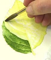 a person holding a knife and cutting up a piece of paper with green leaves on it