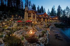 an outdoor fire pit surrounded by rocks and trees at night with lit up lights on it