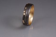 a gold and black ring with diamonds on the inside, sitting on a gray surface