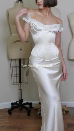 a woman in a white dress standing next to a mannequin