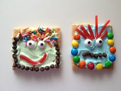 two decorated cookies sitting on top of a white table next to each other in the shape of faces