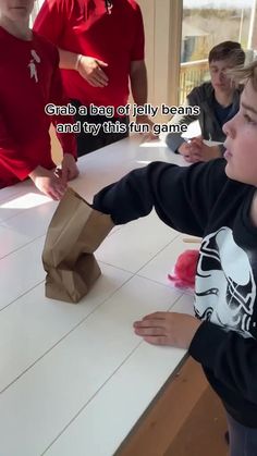 a young boy holding a paper bag over a table