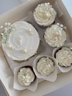 a box filled with cupcakes covered in white frosting and topped with flowers