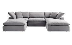 a grey sectional couch with pillows on it's back and arms, facing the camera