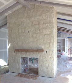 an unfinished fireplace in the middle of a room with white walls and beams on it