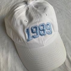 a white hat with the number 991 embroidered on it sitting on a bed sheet