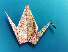 an origami bird made out of maps on a blue background