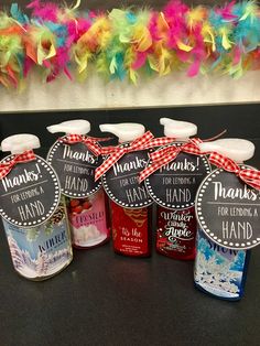 hand sanitizers are lined up on a table with colorful feathers in the background