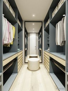 an empty walk in closet with clothes hanging on the walls and wooden shelves, along with a stool