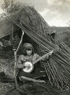 an old black and white photo of a woman sitting in front of a teepee