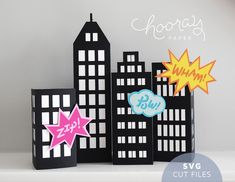 three black and white paper cut out buildings with pink stars in the middle, one blue and one green