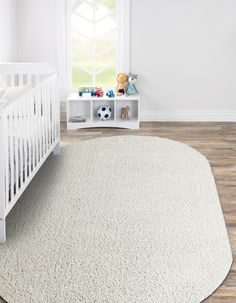 a baby's room with a white crib and teddy bear on the floor