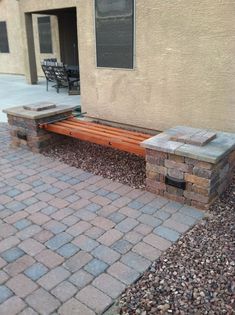 a brick bench sitting in front of a building next to a stone walkway and patio