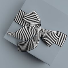 a black and white bow sitting on top of a gray box with striped ribbon around it