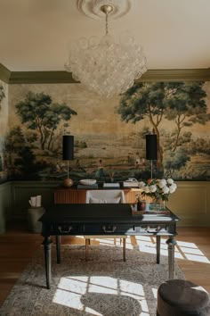 a room with a large painting on the wall and a chandelier hanging from the ceiling