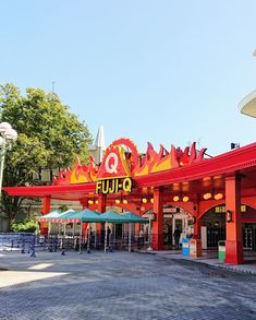 the entrance to an amusement park with lots of tables and umbrellas in front of it