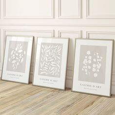 three framed art prints sitting on top of a wooden floor