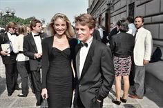 two people standing next to each other in formal wear and tuxedos at an event