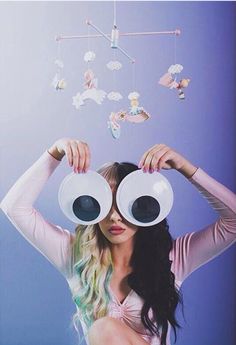 a woman holding two large white cups over her eyes with butterflies coming out of them