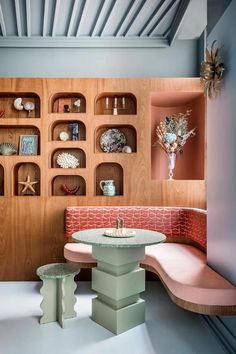 a table and bench in a room with shelves on the wall behind it, along with other furniture