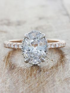 an oval cut diamond ring on top of a wooden surface