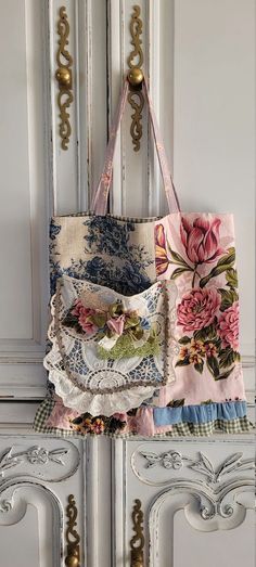 a purse hanging on the side of a white cabinet next to a flowered bag