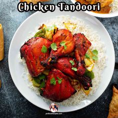 chicken tandoori served over rice on a white plate with garnishes