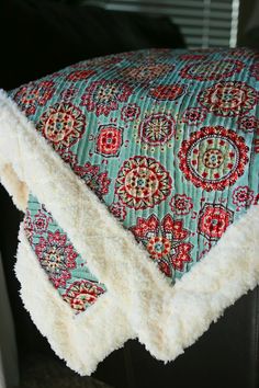 a close up of a pillow on a chair with a blanket over the back of it