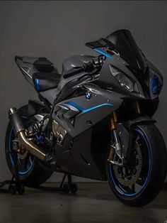 a black and blue motorcycle is parked in a dark room with no one around it