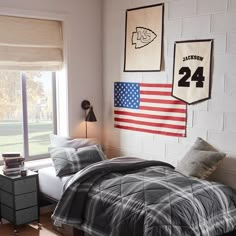 a bed room with a neatly made bed and an american flag hanging on the wall