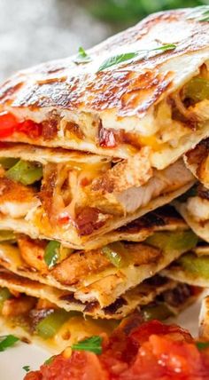 several quesadillas stacked on top of each other with tomatoes and green peppers