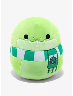 a green stuffed animal with a scarf around it's neck and eyes, sitting on a white surface