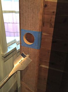 a wooden door with a hole in it and a wrench stuck to the side