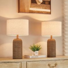 two lamps sitting on top of a wooden dresser