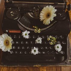 an old fashioned typewriter with daisies on the keys and paper attached to it