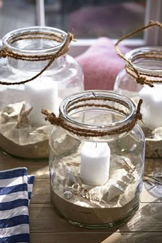 three glass jars filled with sand and candles