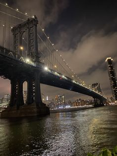 the bridge is lit up at night and it looks like it's going over the water