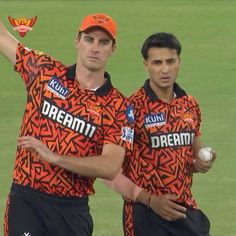 two men standing next to each other on top of a field holding a ball in their hands