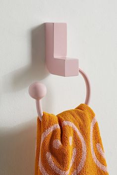 an orange towel hanging on the wall next to a pink hook with a smiley face drawn on it