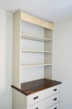 a white bookcase with two drawers and a wooden counter top in the corner of a room