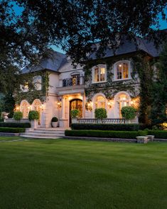 a large white house sitting on top of a lush green field next to a tree