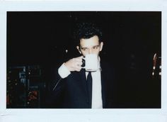 a man in a suit drinking from a coffee cup