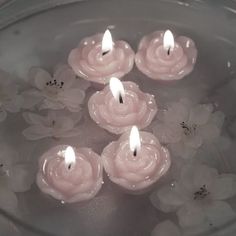 small candles are floating in water with white flowers