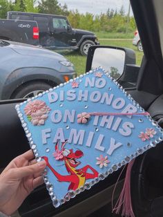 a hand holding up a blue graduation cap that says, no dishono on this family